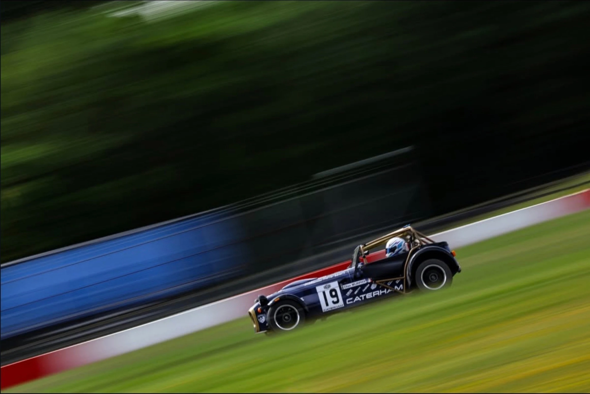 The number 19 Caterham on track at Donington Park, panning with the background blurred by speed.